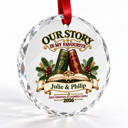 A personalized round clear crystal Christmas ornament with a red hanging ribbon, featuring printed text reading 'OUR STORY IS MY FAVOURITE Julie & Philip FIRST CHRISTMAS AS A MARRIED COUPLE 2026' with decorative books, greenery, and berries on a white background.