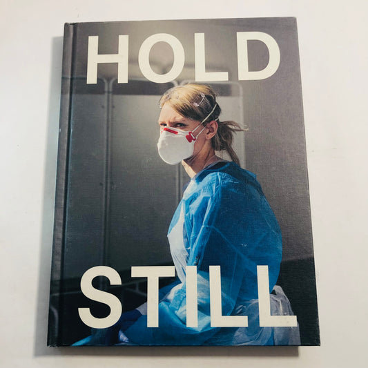 Book cover with a person in medical attire and text 'HOLD STILL' on a plain background