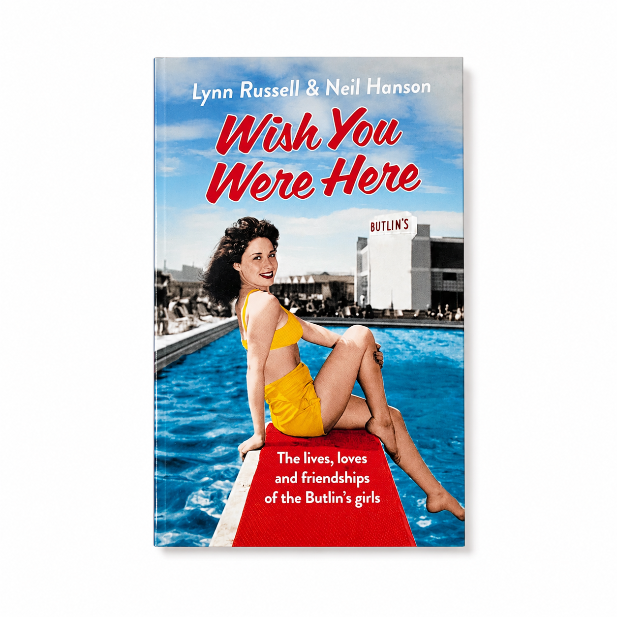 The book cover of 'Wish You Were Here' by Lynn Russell & Neil Hanson, featuring a retro illustration of a woman in a yellow swimsuit sitting on the edge of a swimming pool with a red diving board. The title is written in large red letters, and the background shows a blue sky and pool water.